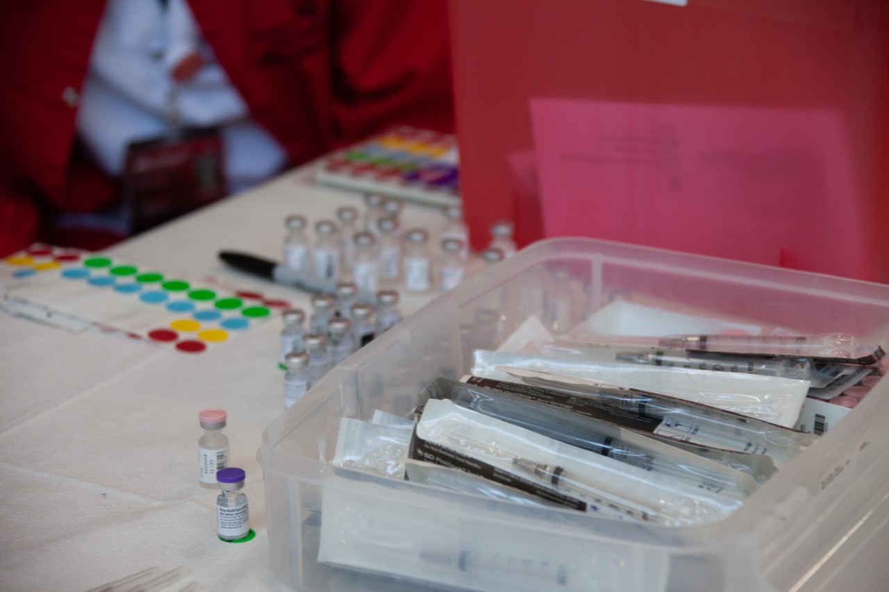 a table with a container of needles and vaccine doses at a COVID-19 vaccination clinic
