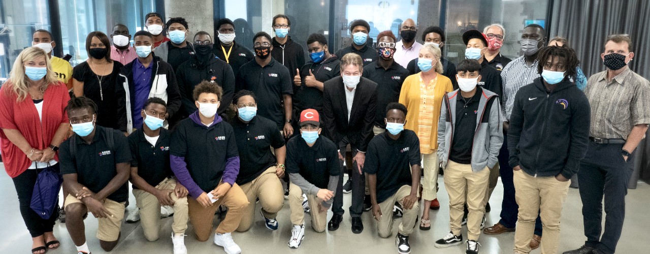 UC's David Adams and Cincinnati Aiken High School students stand wearing PPE masks inside UC's 1819 Innovation Hub.
