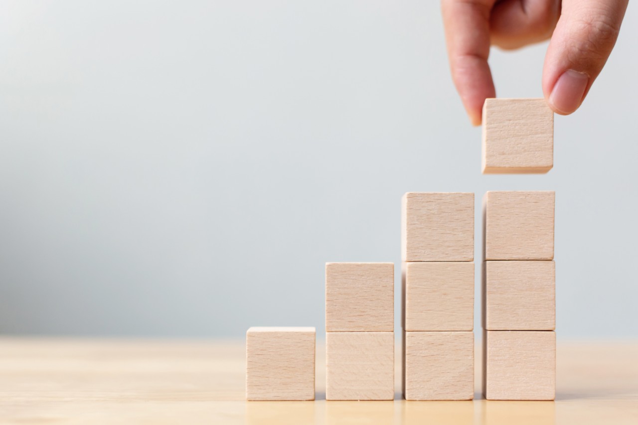 Hand arranging wood block stacking as step stair on wooden table. Business concept for growth success process. Copy space