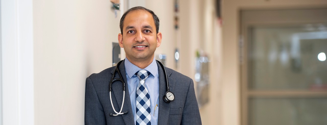 Doctor wearing suit stands smiling in a clinic