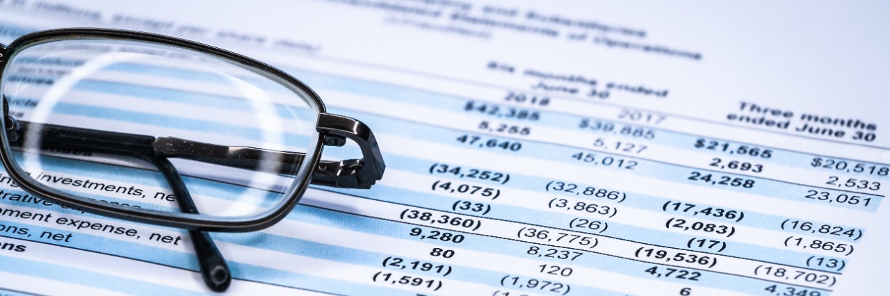 Stock image of a profit and loss sheet with glasses folded up on top.