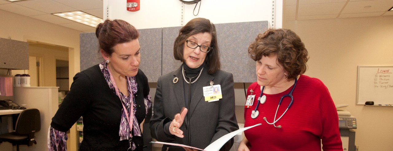 Three women discuss a patient case file