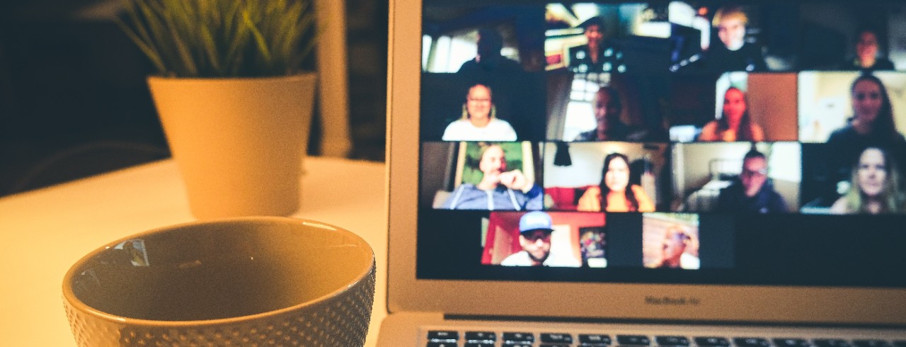 A closeup of a coffee cup near a laptop with an open Zoom call.