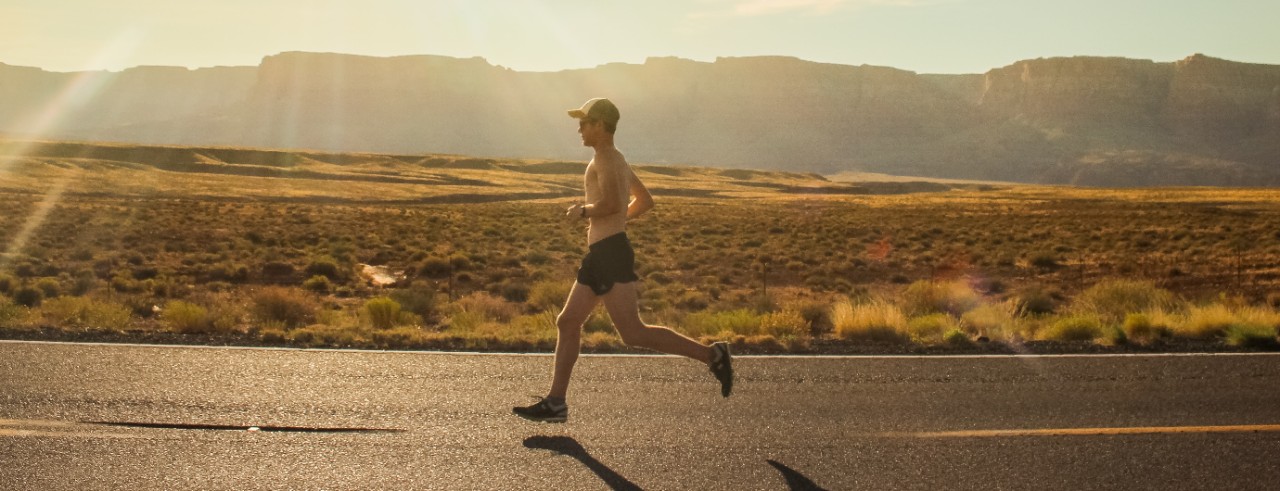 man running on road near desert and hills