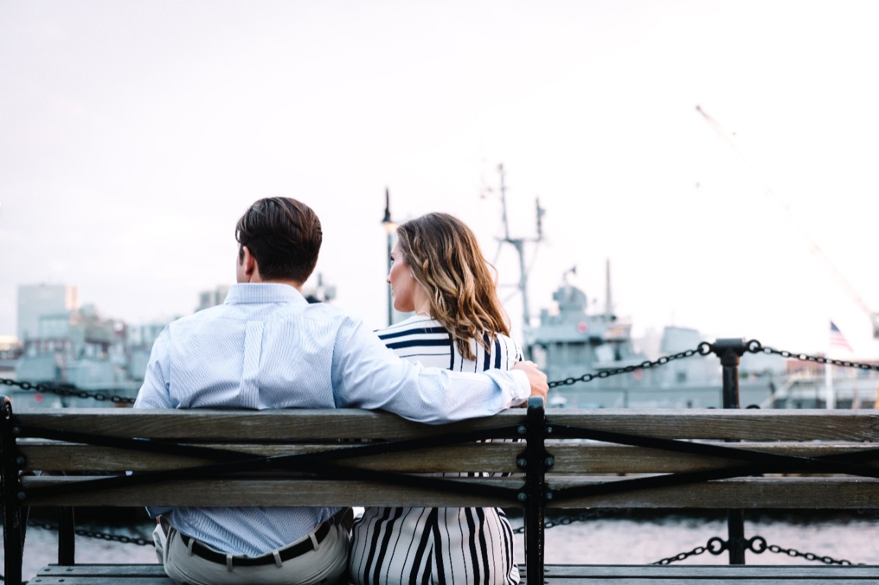 A couple sits on a bench outside