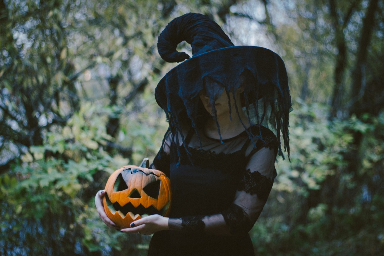 woman in witch costume holding a pumpkin 
