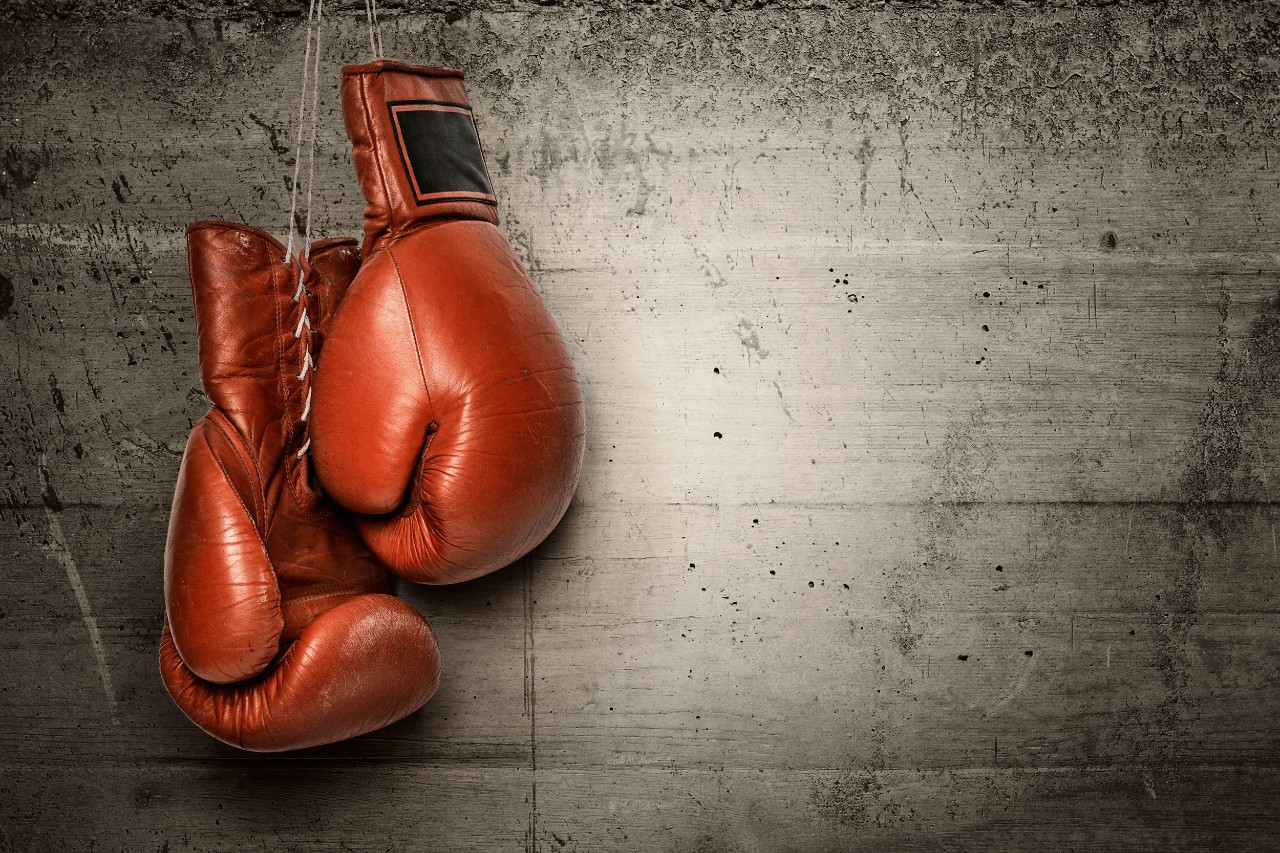 red boxing gloves hanging against a cement wall