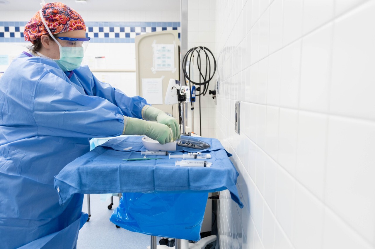 a woman doctor in blue scrubs prepares a surgical table