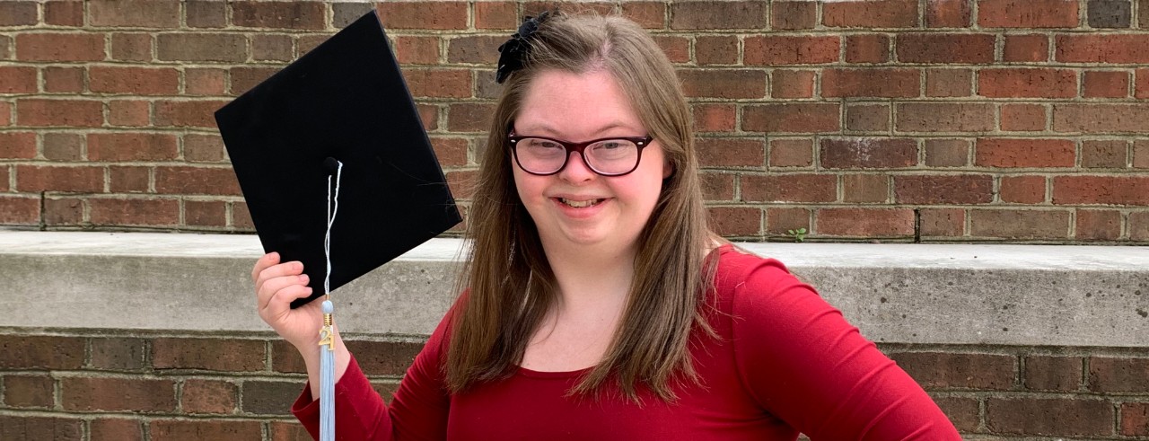 Brennan Eve in a red dress holding her TAP graduation certificate