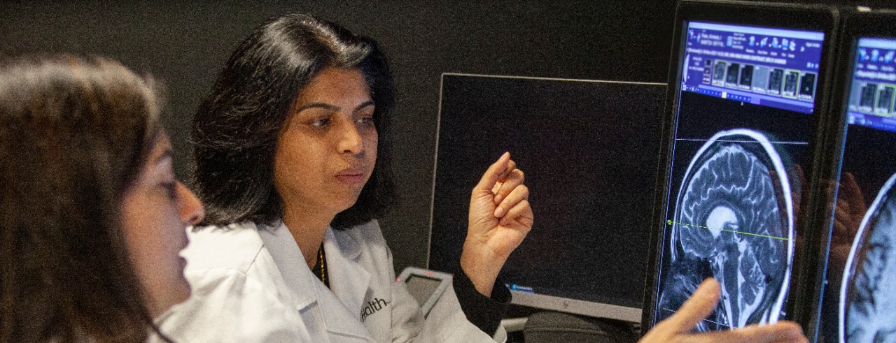 Two doctors examine brain scans on a computer screen