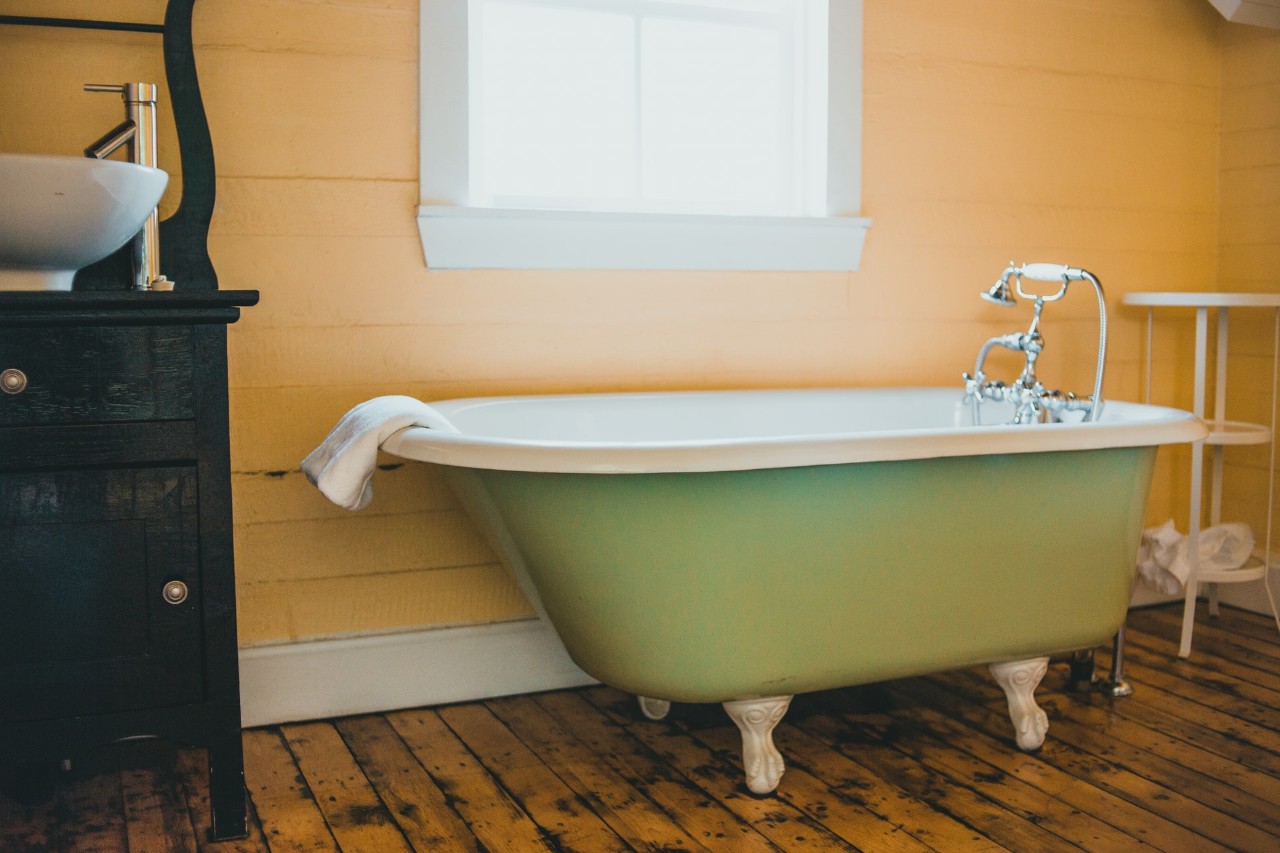 old fashioned soaking tub in yellow bathroom. tub is green.