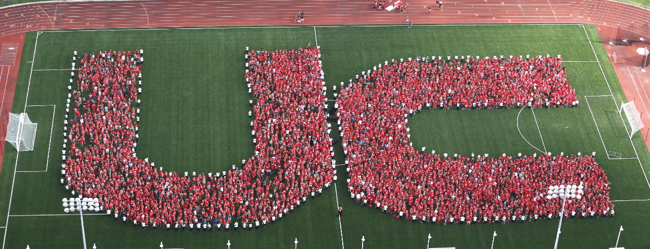 aerial photo of students forming UC on football field