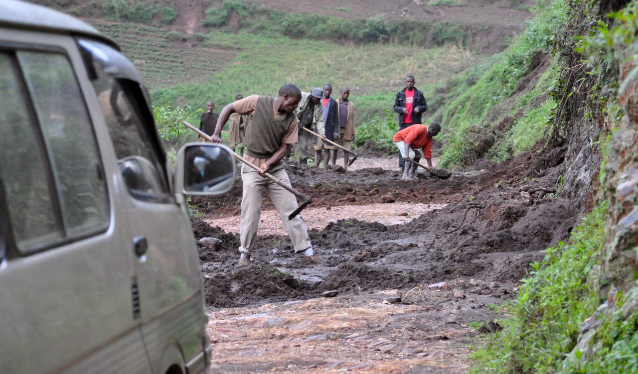 Rural residents in Uganda clear a road after heavy rain caused a mudslide on a dirt road.