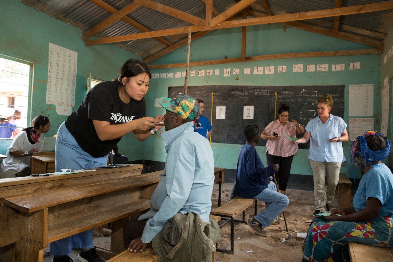 A UC medical student examines a patient in a school classroom used as a makeshift medical clinic.