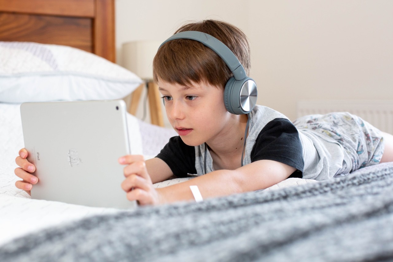 teen on bed with a laptop and headphones