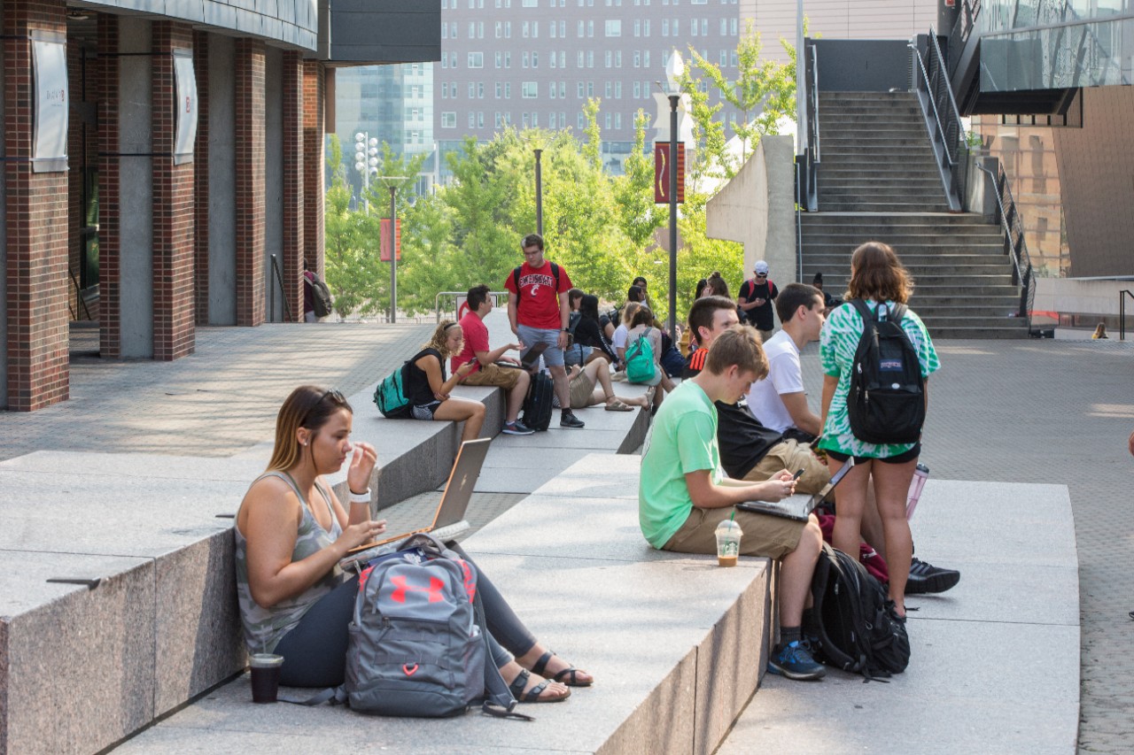 Students sitting outside of Tangeman University Center and Main Street.