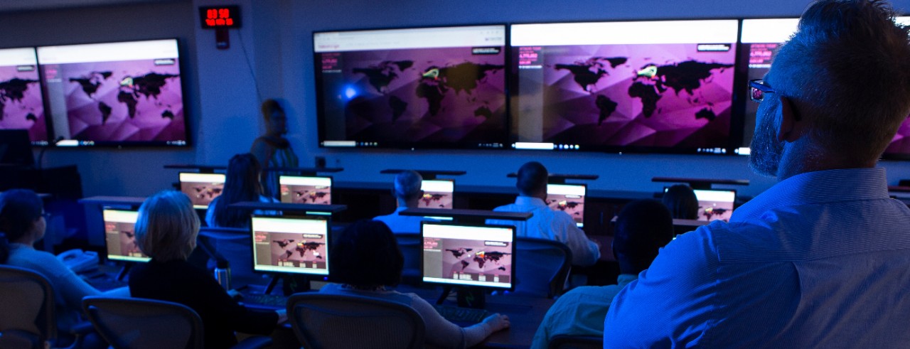 people sitting at computers in a darkened room