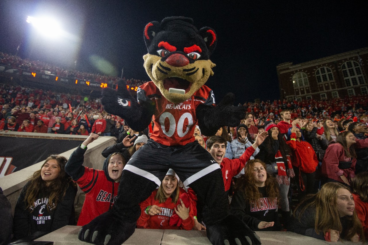 Bearcat show standing on Nippert Stadium bleachers with fans in the background