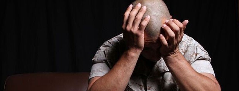 A soldier looks distressed, sitting with his head in his hands