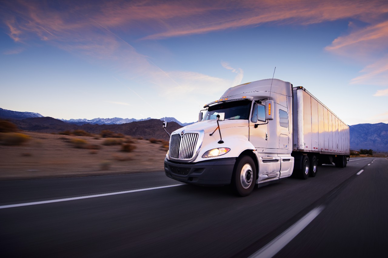 A white rig truck drives on the open road.