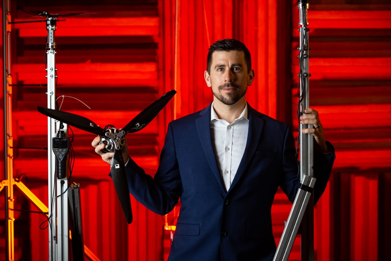 Daniel Cuppoletti stands in an anechoic chamber with a scale-model propeller.