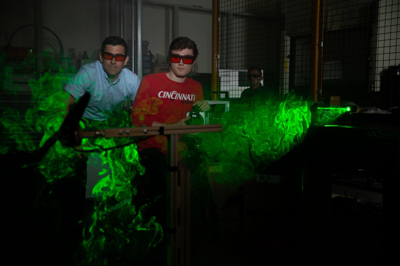 Daniel Cuppoletti and an aerospace engineering student use a laser to illuminate air vortices from a propeller.