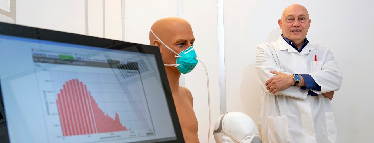 Dr. Sergey Grinshpun stands by a computer monitor and mannequin with an N95 facemask