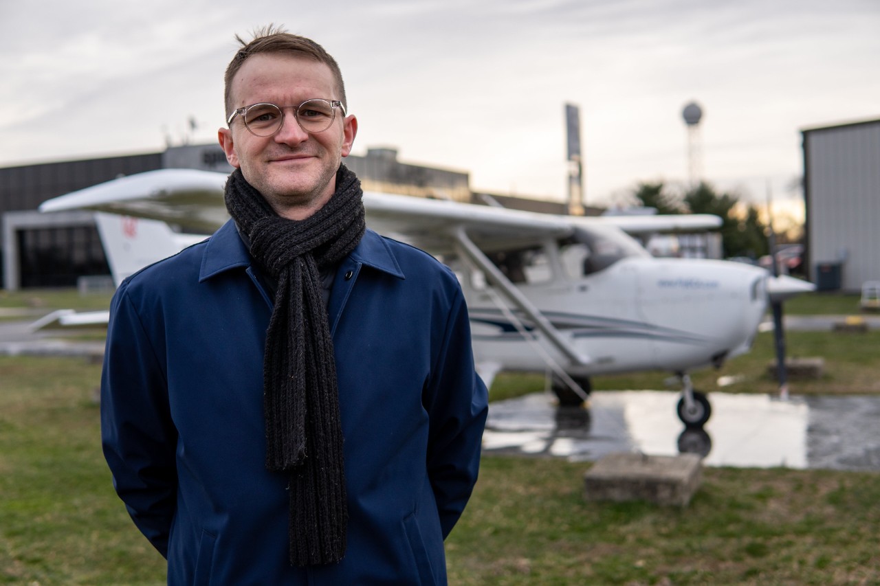 Seth Cooper stands in front of small airplane.