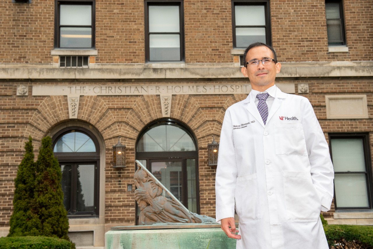 a man in a white lab coat standing outside Holmes Hospital