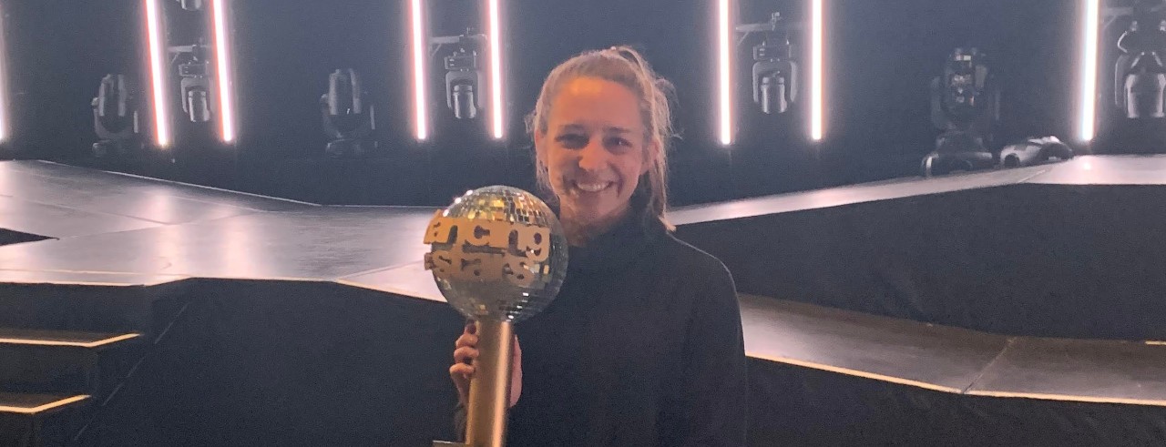 Schneider on stage holding the Dancing with the Stars Mirrorball Trophy 