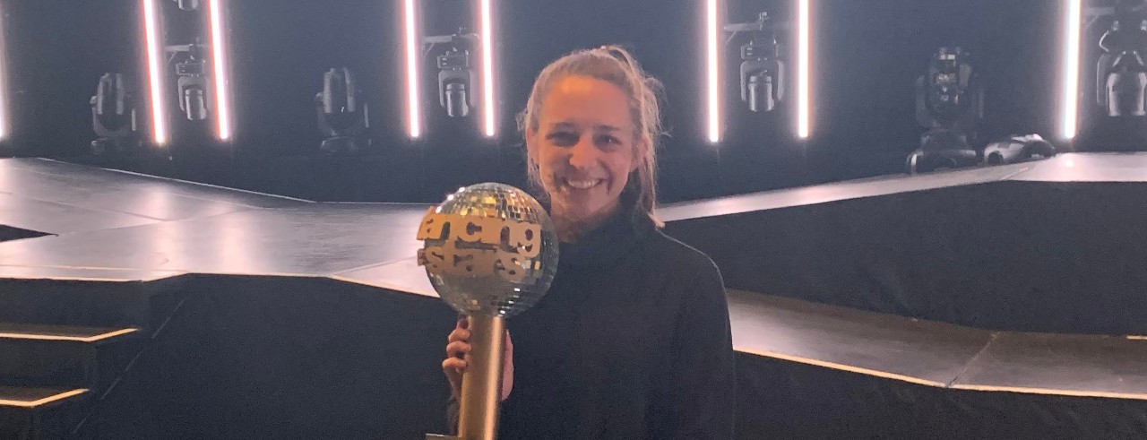 Schneider on stage holding the Dancing with the Stars Mirrorball Trophy