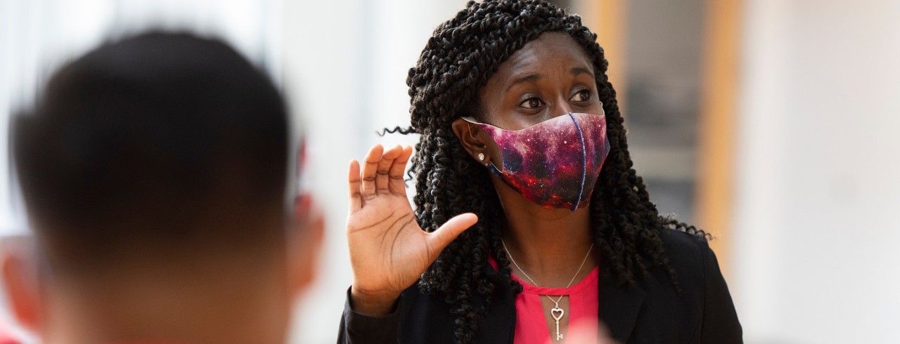 Black woman wearing a mask teaching sign language