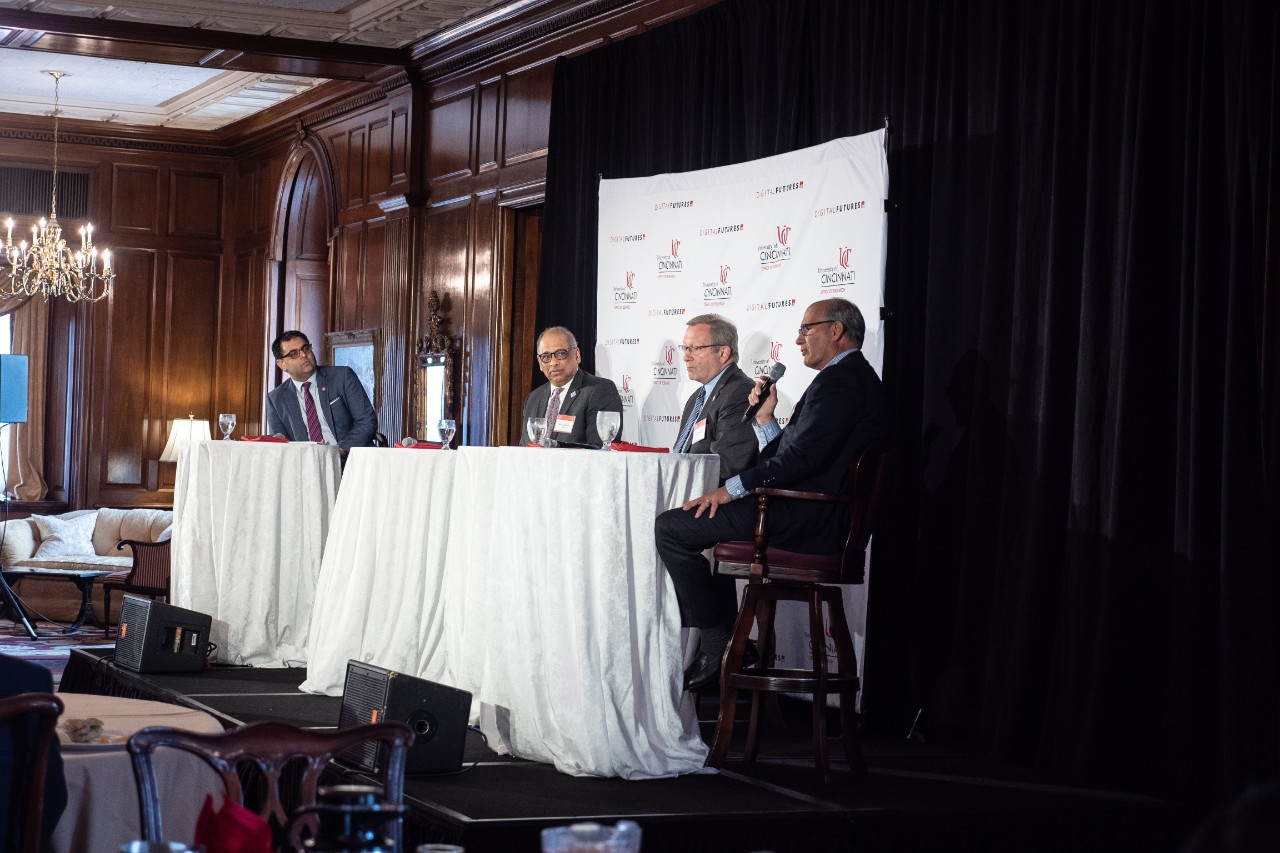 Four men on a stage as part of a panel discussion.