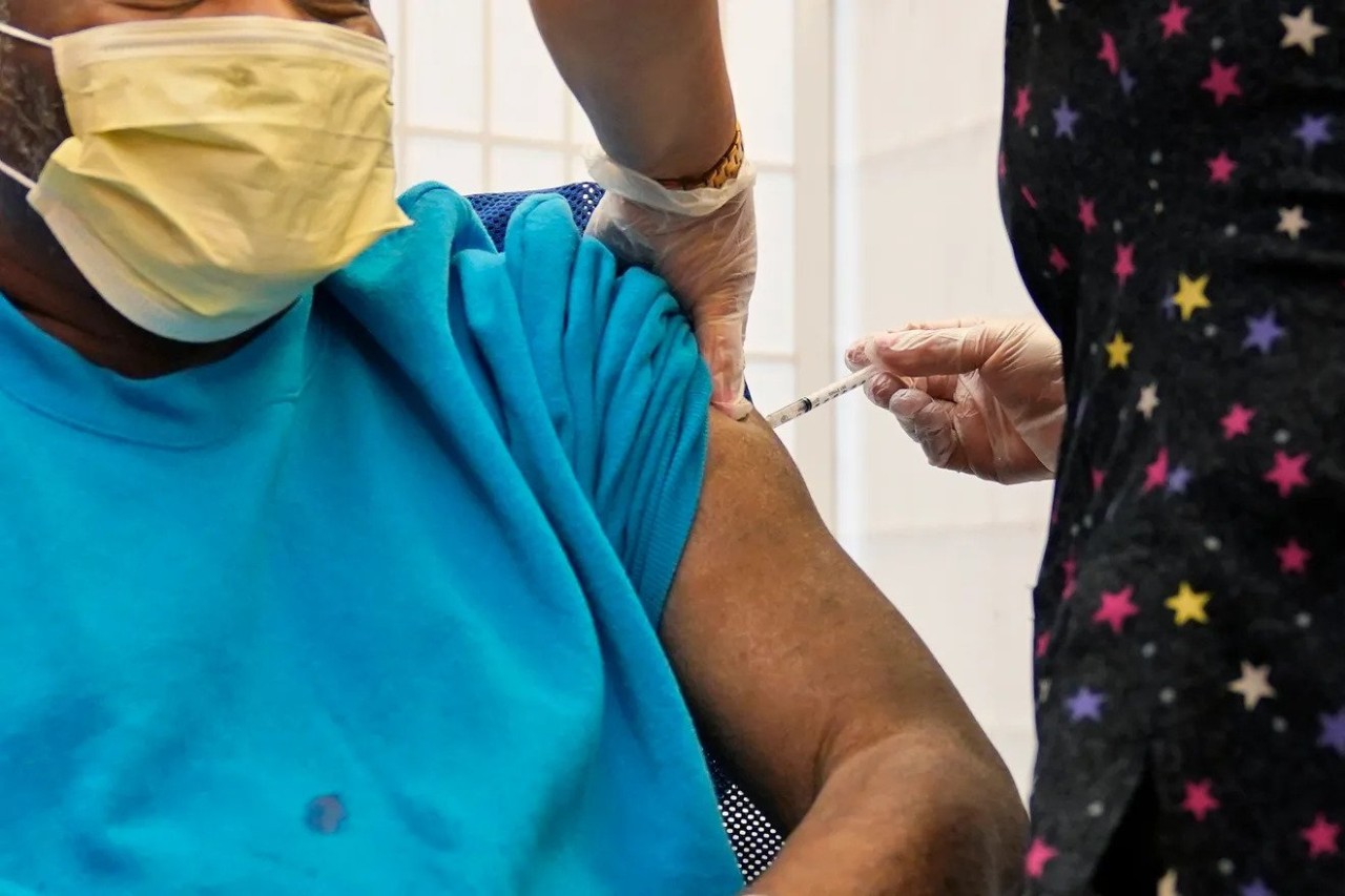 a person wearing a facemask receiving a booster shot