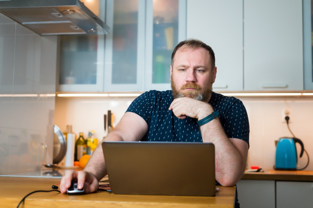 A man working from home looks at a laptop.