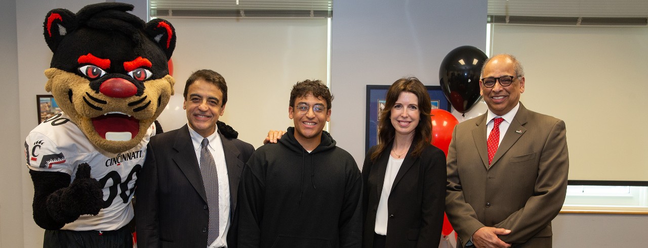 Truman Scholarship winner Adam Elzarka (center) is congratulated by the Bearcat, his father, UC professor of construction management Hazem Elzarka, director of nationally competitive awards Jenny Hyest, and UC president Neville Pinto.