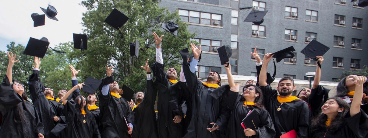 Students toss their mortar boards into the air outside Fifth Third Arena.