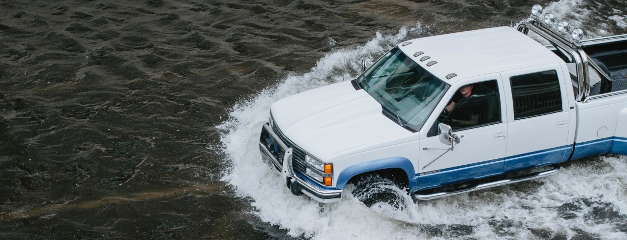 A pickup truck drives through flood waters.