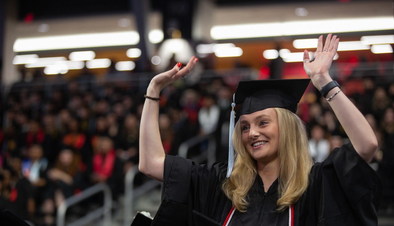 A UC graduate celebrates on the floor of Fifth Third Arena.