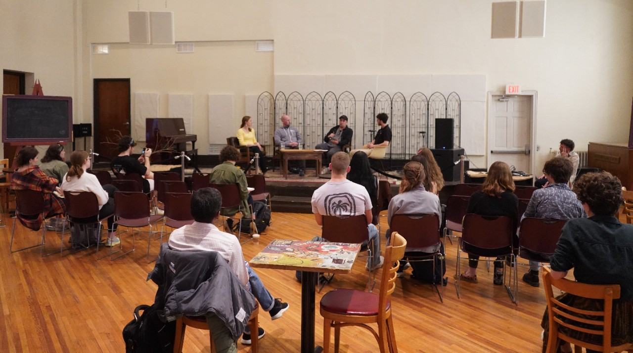 Attendees of a sustainability panel sit in chairs and listen to speakers.