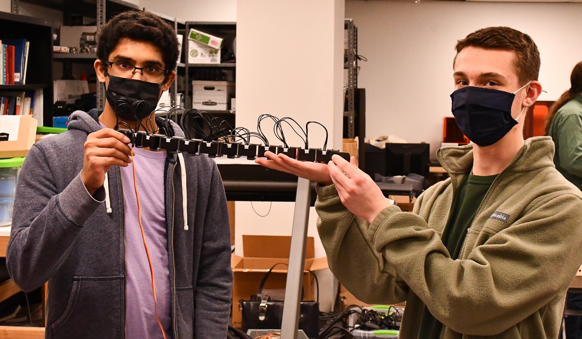 Students hold up a robotic snake in a UC classroom.