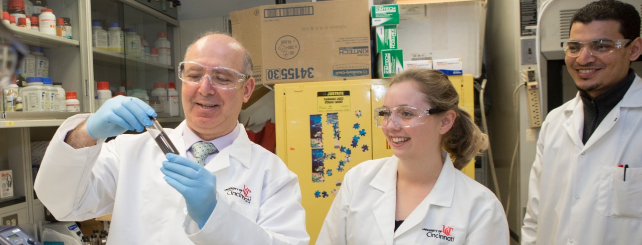 Dion Dionysiou holds a vial while speaking to students in a lab