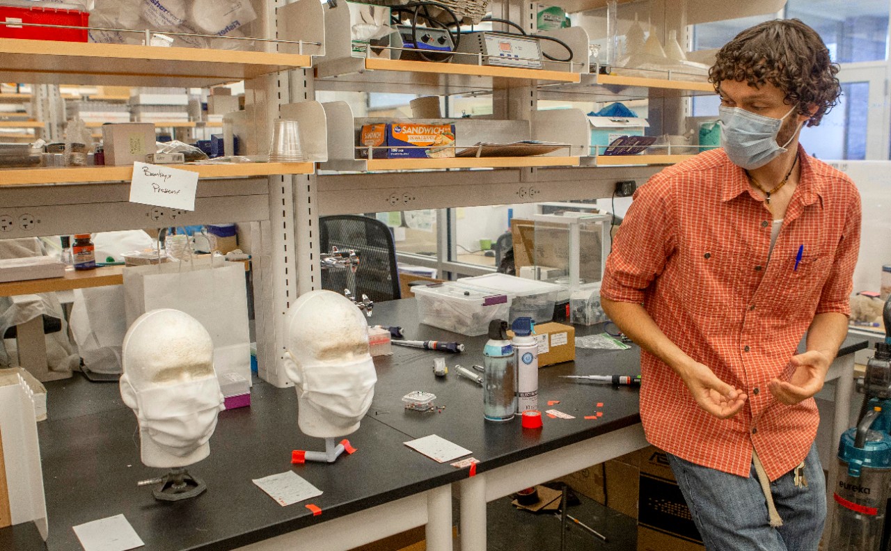 Adam Parlin stands next to mask-covered dummies in a biology lab.