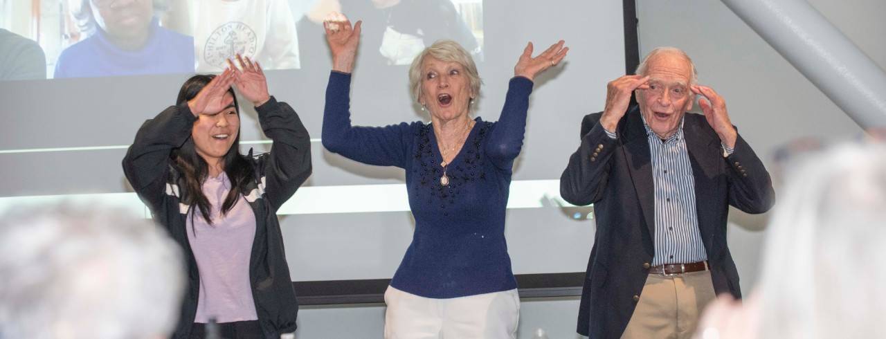 Community members and a student dance in a classroom