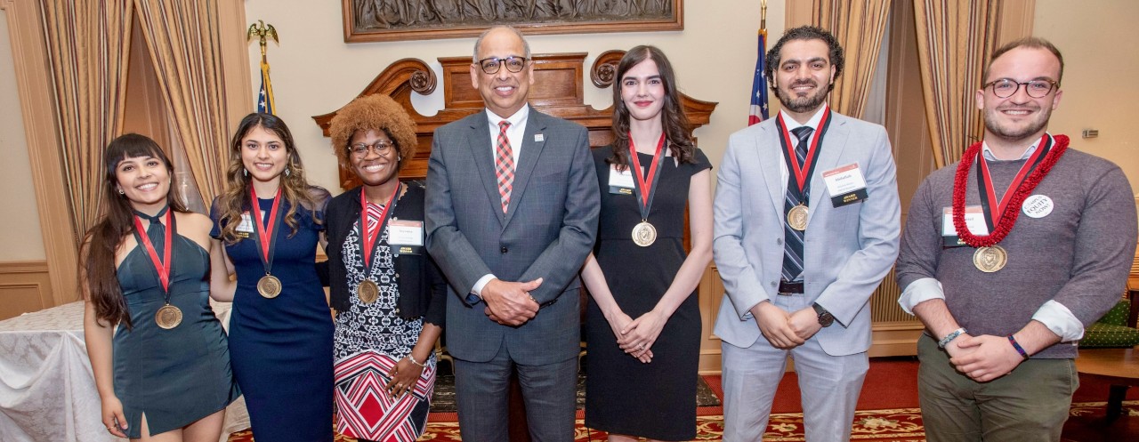 UC president Pinto in center flanked by three students on either side at the 2022 PLME awards