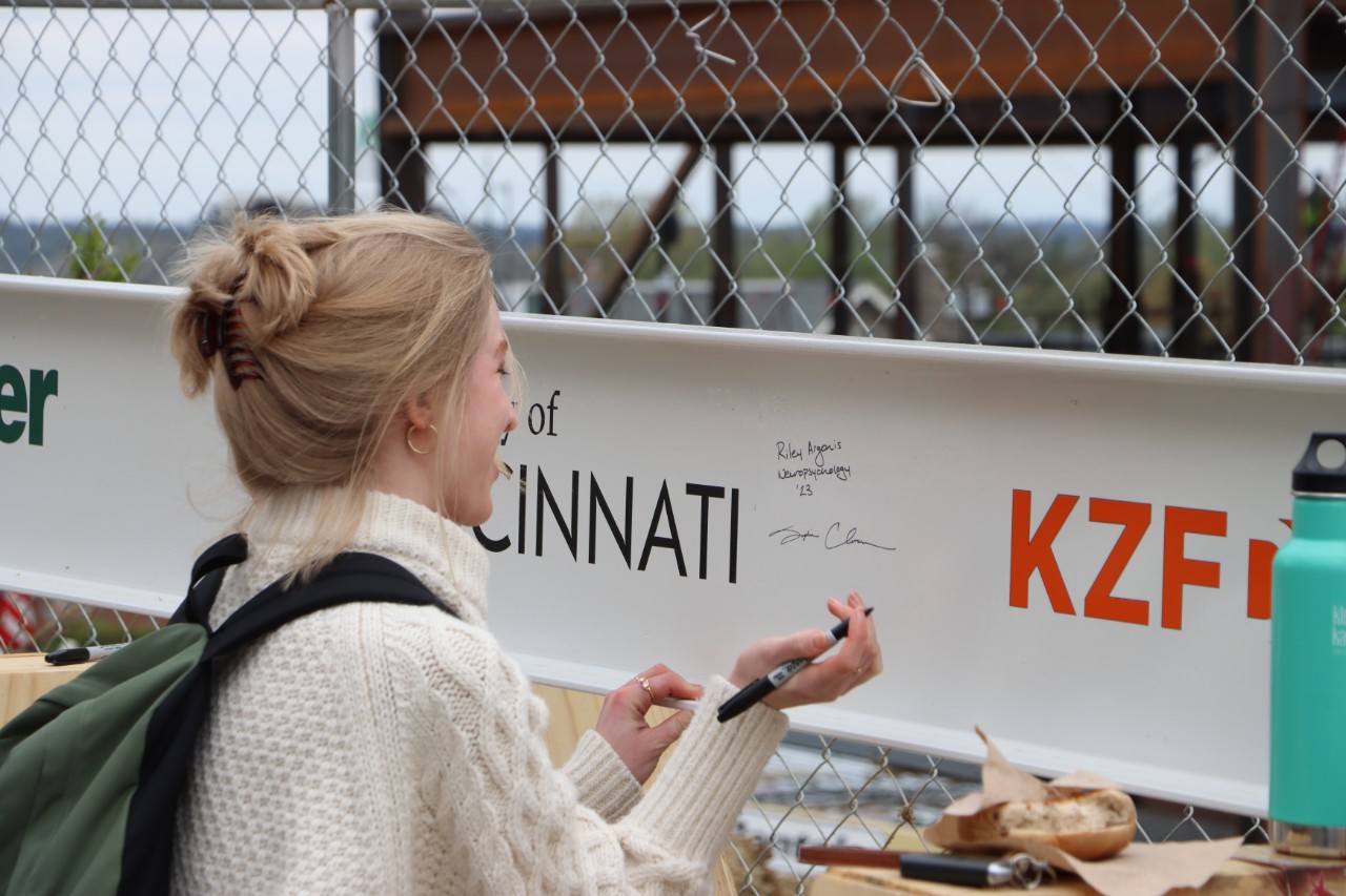 Student adds her signature to the final beam signing for UC's Clifton Court Hall.