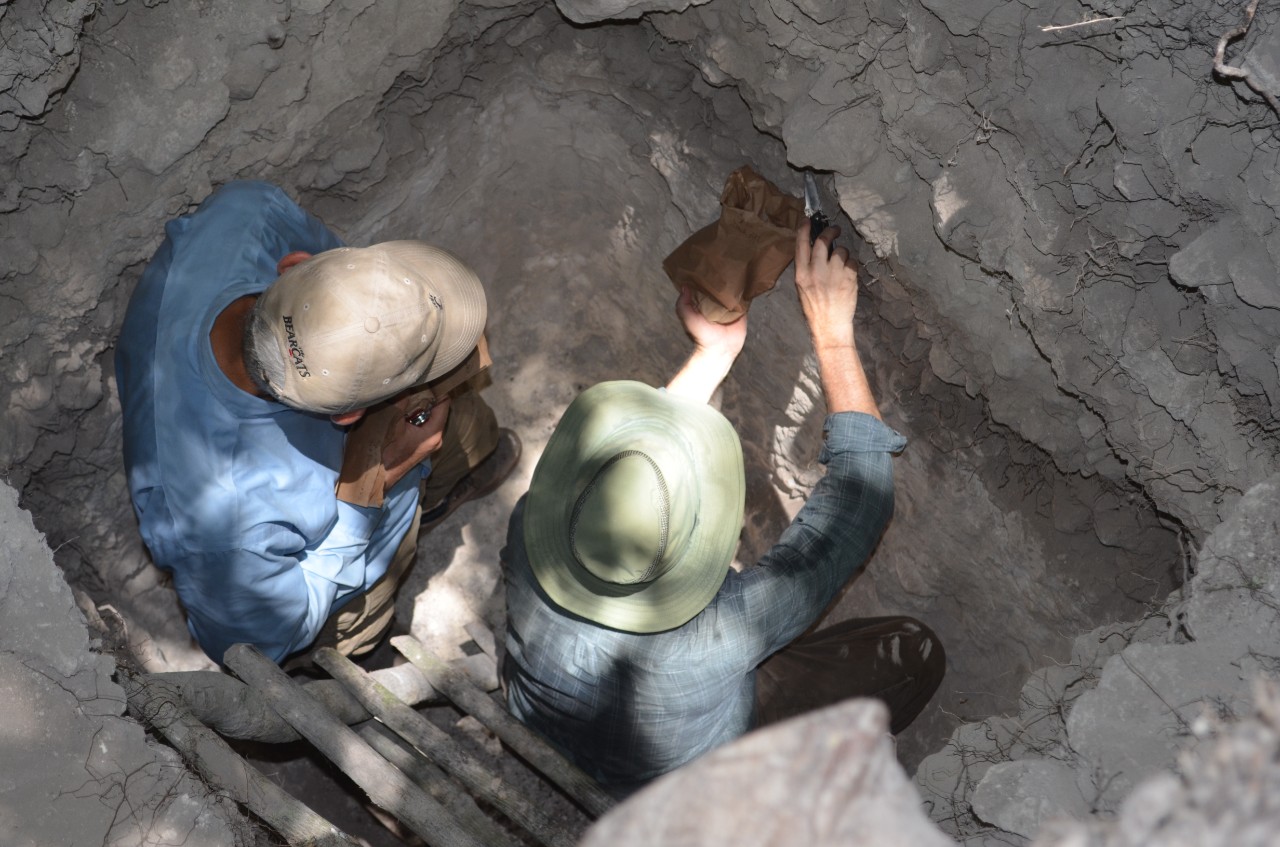 An overhead view of two researchers working in an excavation.