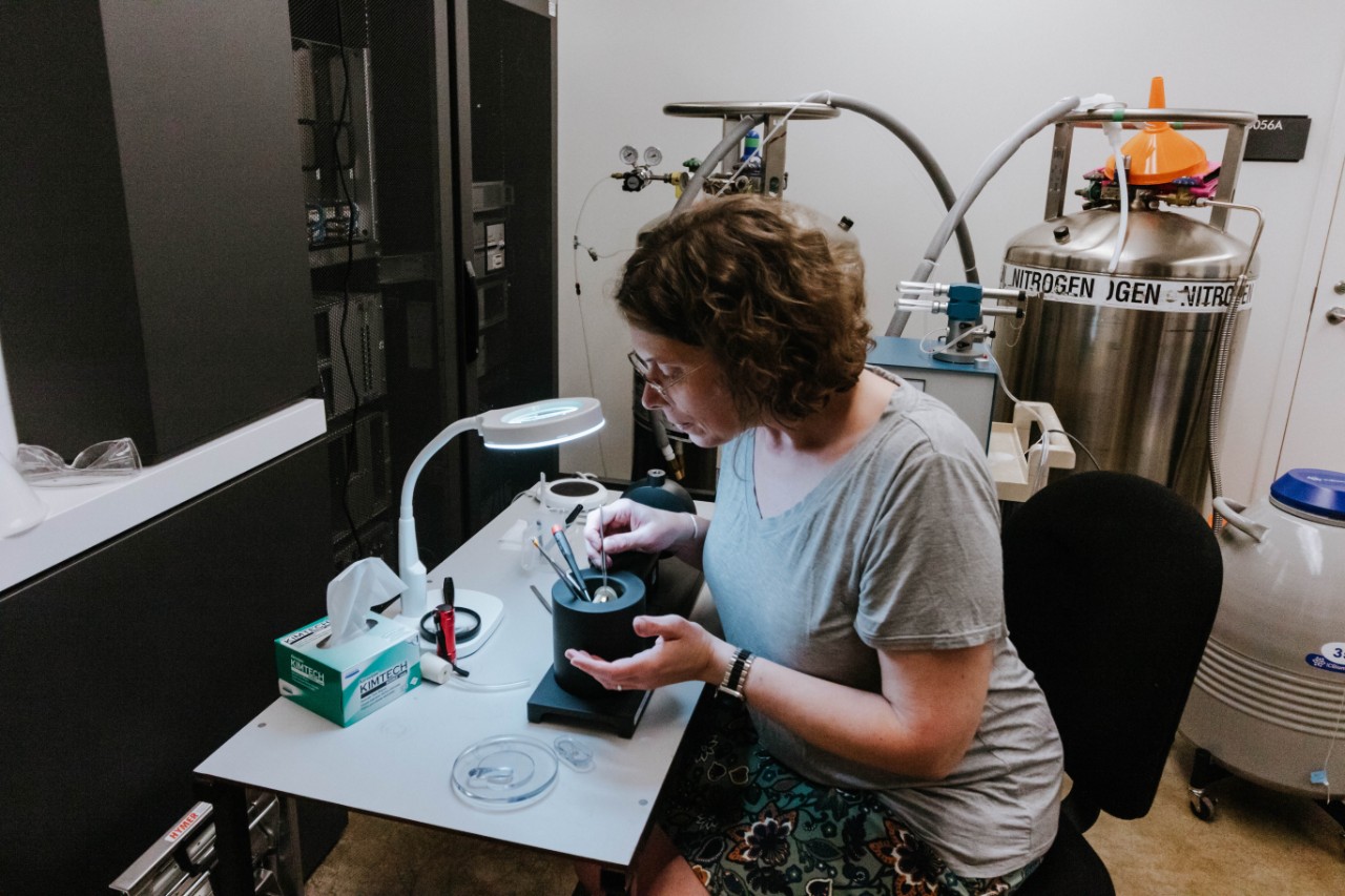 a woman uses an instrument in a cryogenic lab