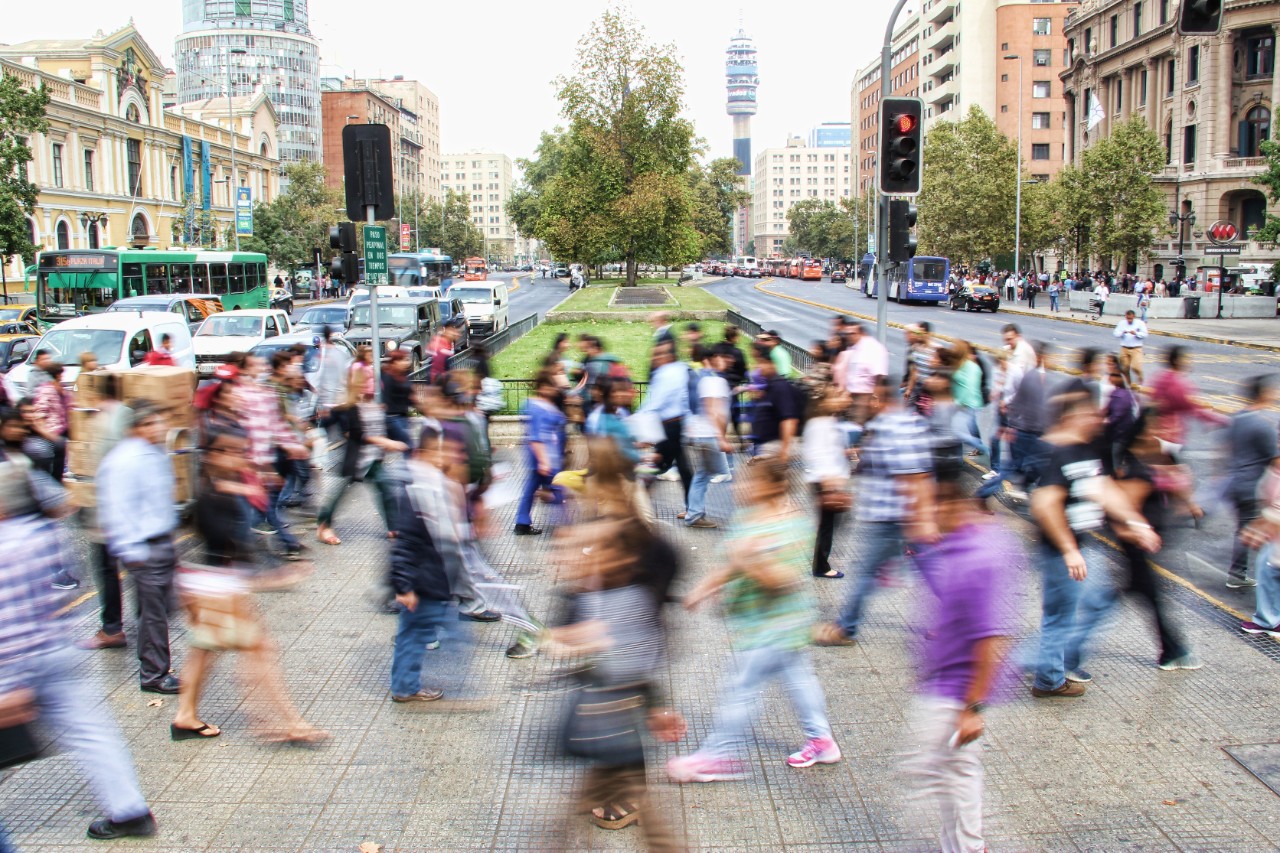 A motion-blurred image of a crowded street full of pedestrians.
