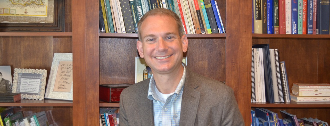 A photo of CCM faculty member Matthew D. Schatt sitting in front of a bookshelf.